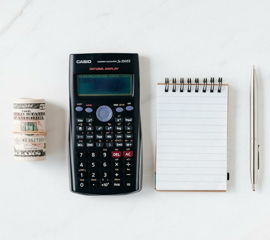 Composition of calculator with paper money and notebook with pen